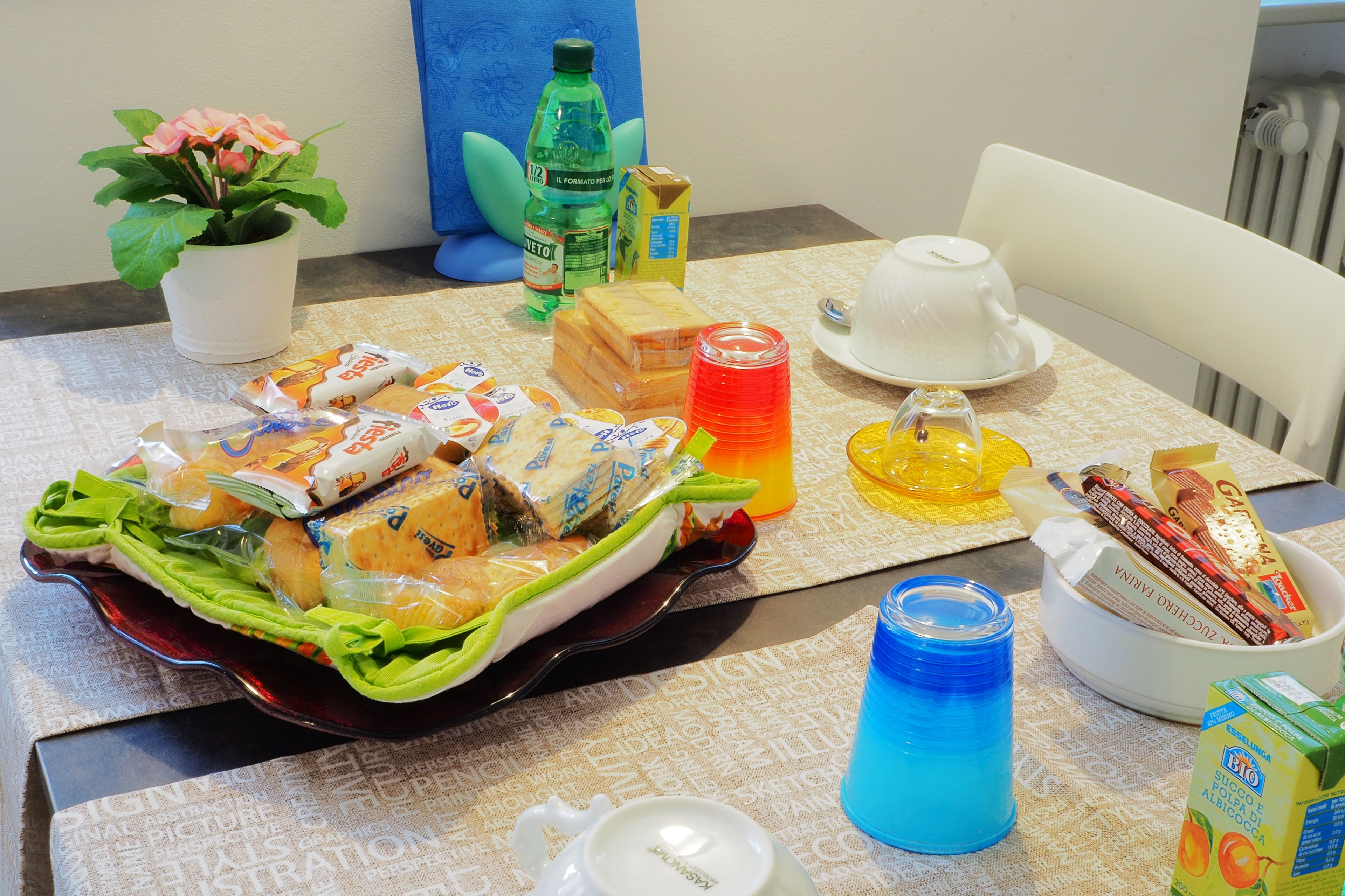 A table set with a variety of food items, including sandwiches and snacks, a potted plant, and a bottle of water.