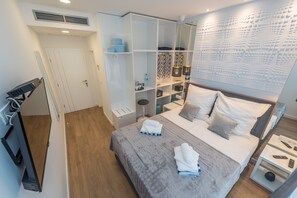 A modern hotel room with a bed, a wardrobe, a vanity, and a desk with a lamp. - Gallery Rooms Zadar (Zadar)