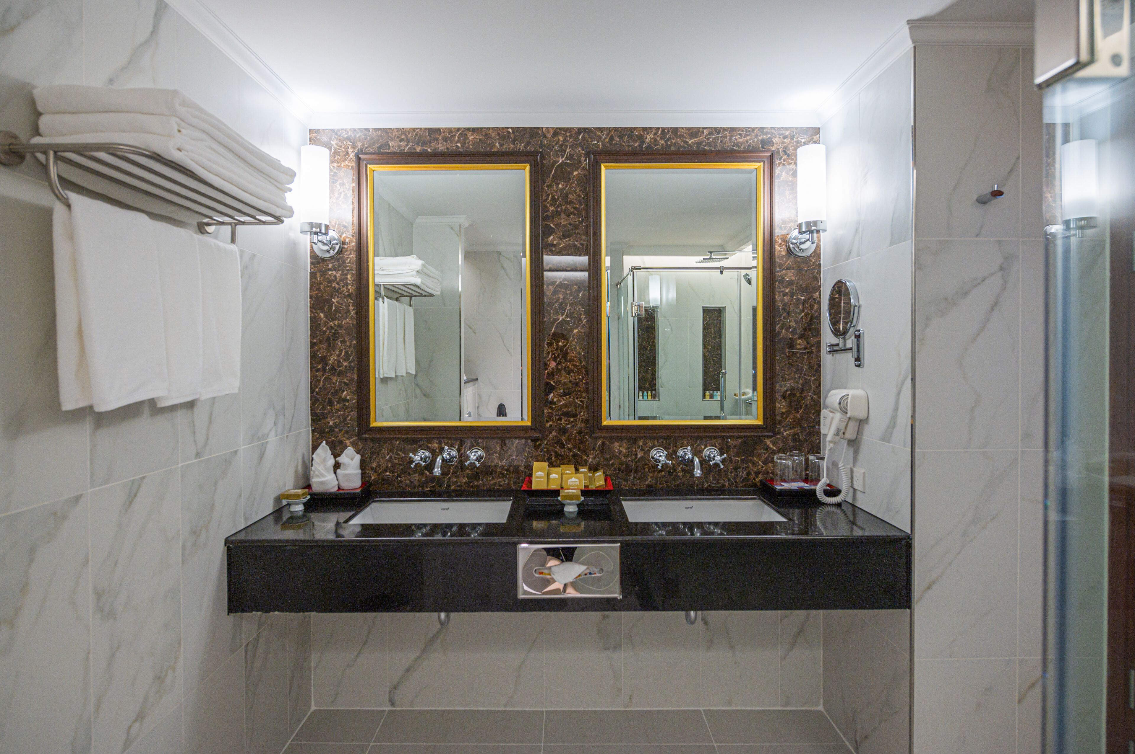 A bathroom with two sinks, a large mirror, and a shower.
