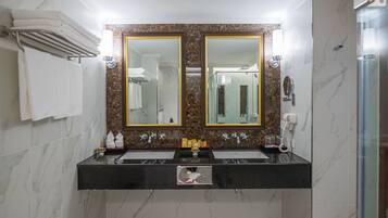 A bathroom with two sinks, a large mirror, and a shower.
