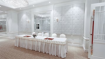 A conference room with a long table, white walls, and a chandelier.