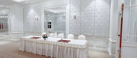 A conference room with a long table, white walls, and a chandelier.