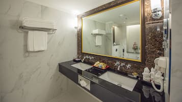 Ein Badezimmer mit zwei Waschbecken, einem großen Spiegel, einem Handtuchhalter und einem Telefon.