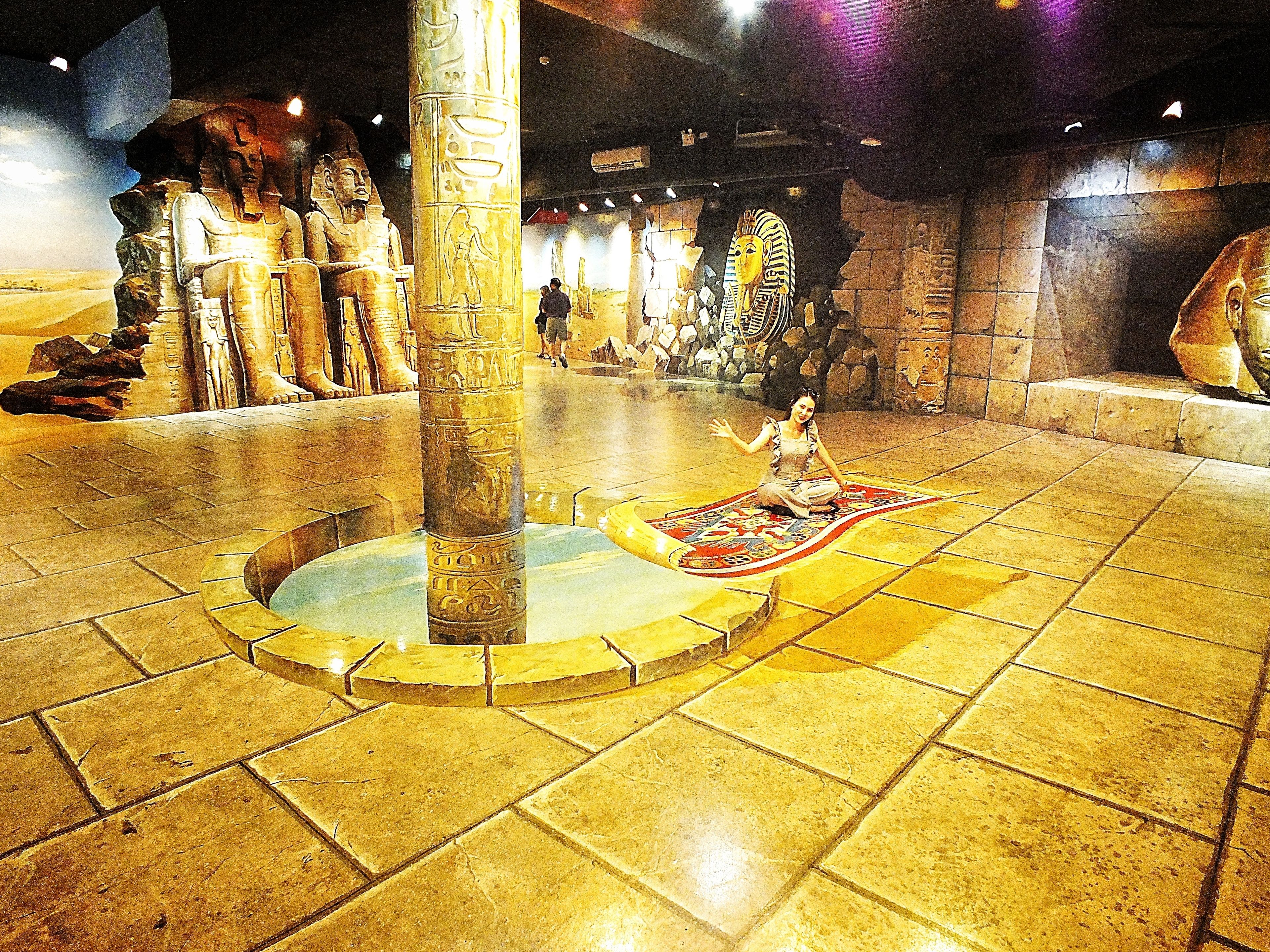 A museum interior with ancient Egyptian artifacts, including a large statue and a sarcophagus.