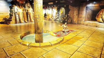 A museum interior with ancient Egyptian artifacts, including a large statue and a sarcophagus.