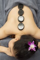 A person lying down with a series of stones placed on their back.