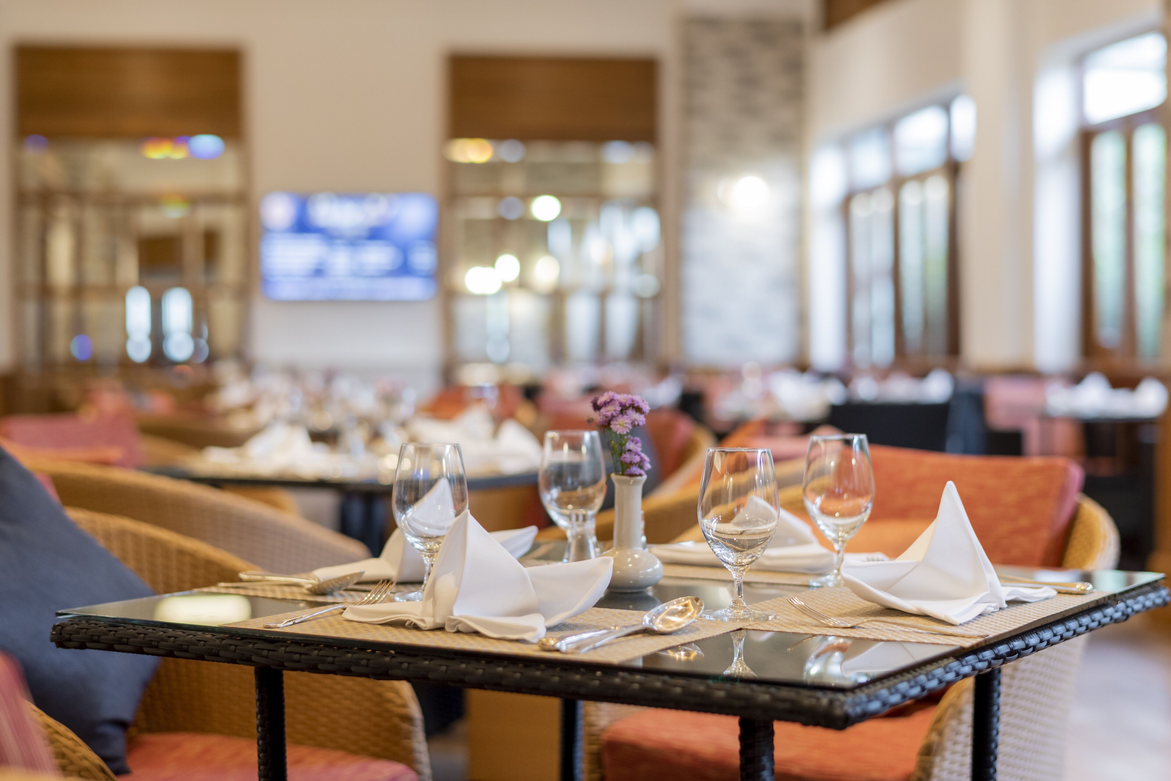 A dining area with tables set for a meal, including wine glasses, plates, and cutlery.