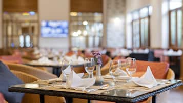 A dining area with tables set for a meal, including wine glasses, plates, and cutlery.