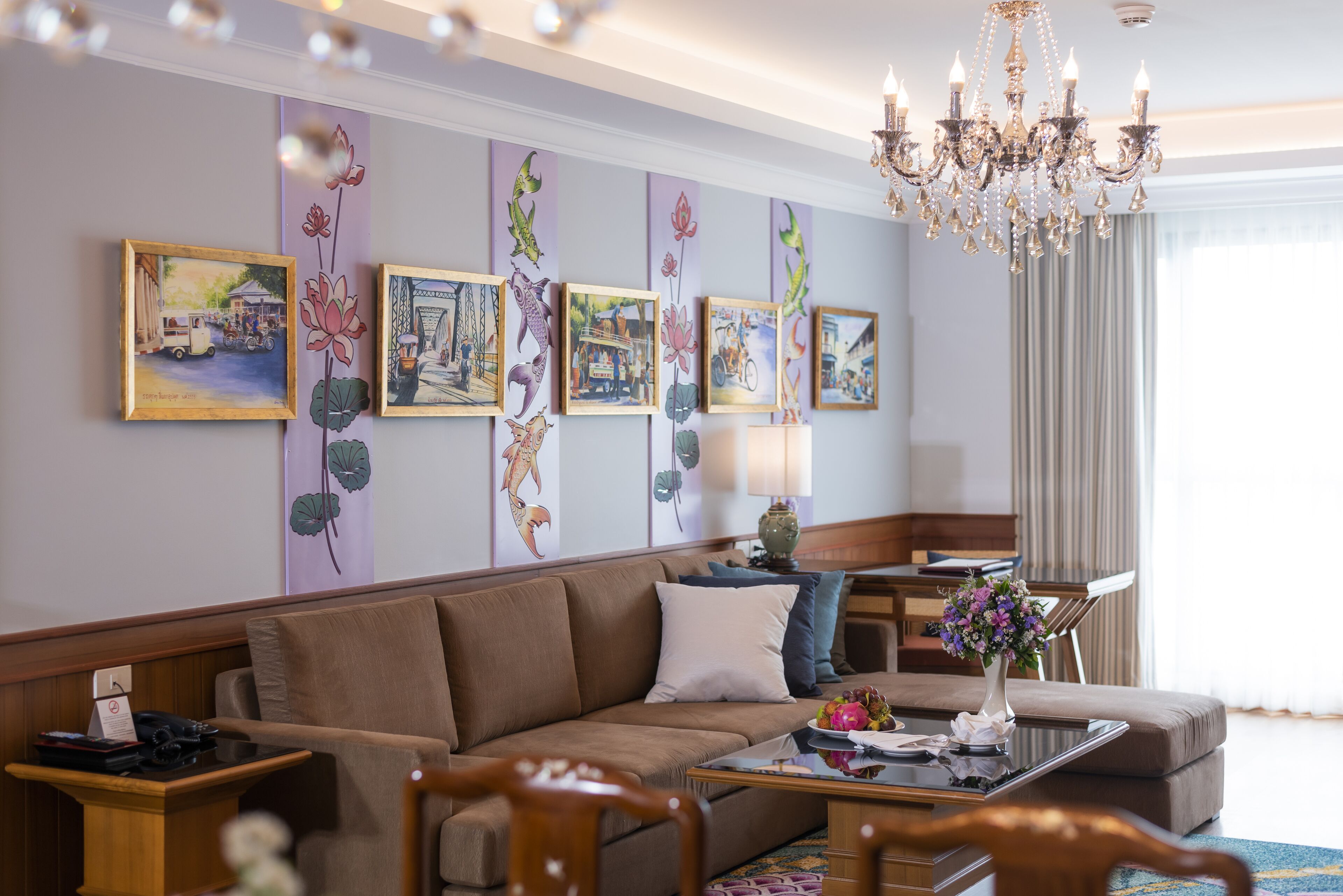 A modern hotel room with a sofa, a coffee table, and a chandelier.