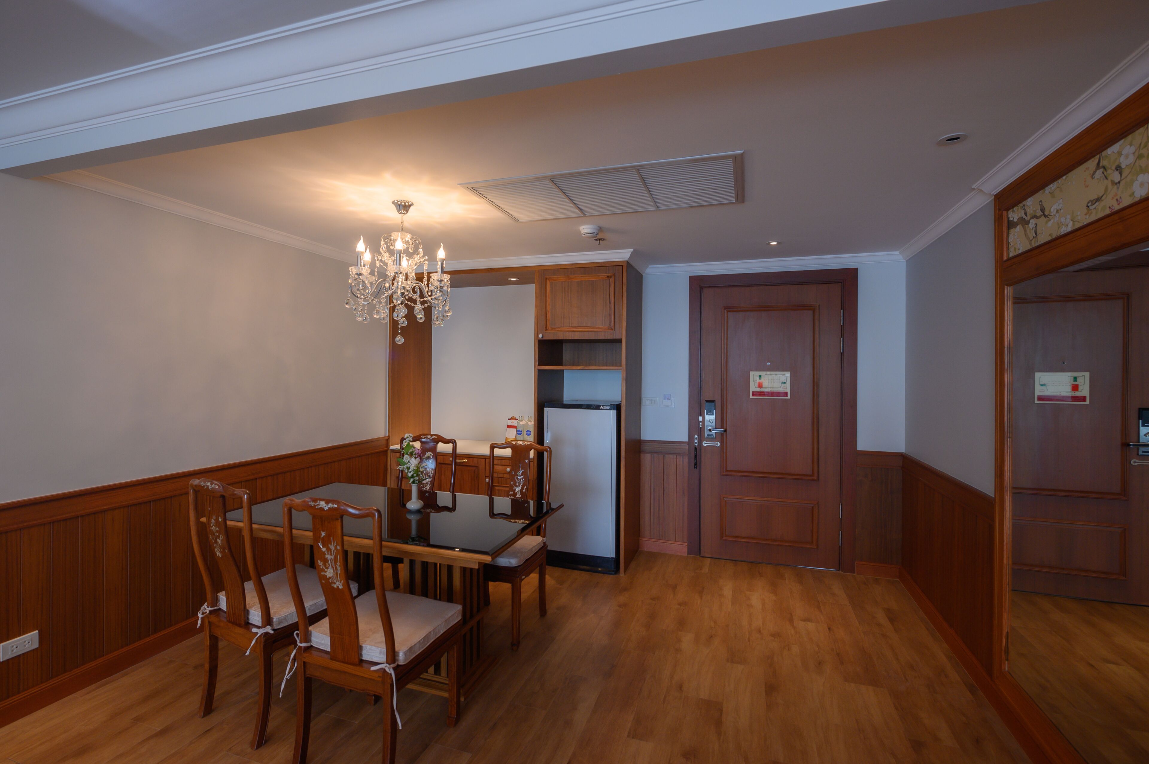 A dining area with a wooden table and chairs, a chandelier, and wooden cabinets.