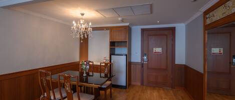 A dining area with a wooden table and chairs, a chandelier, and wooden cabinets.