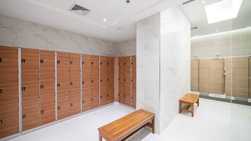 A modern locker room with wooden lockers, a wooden bench, and a marble wall.