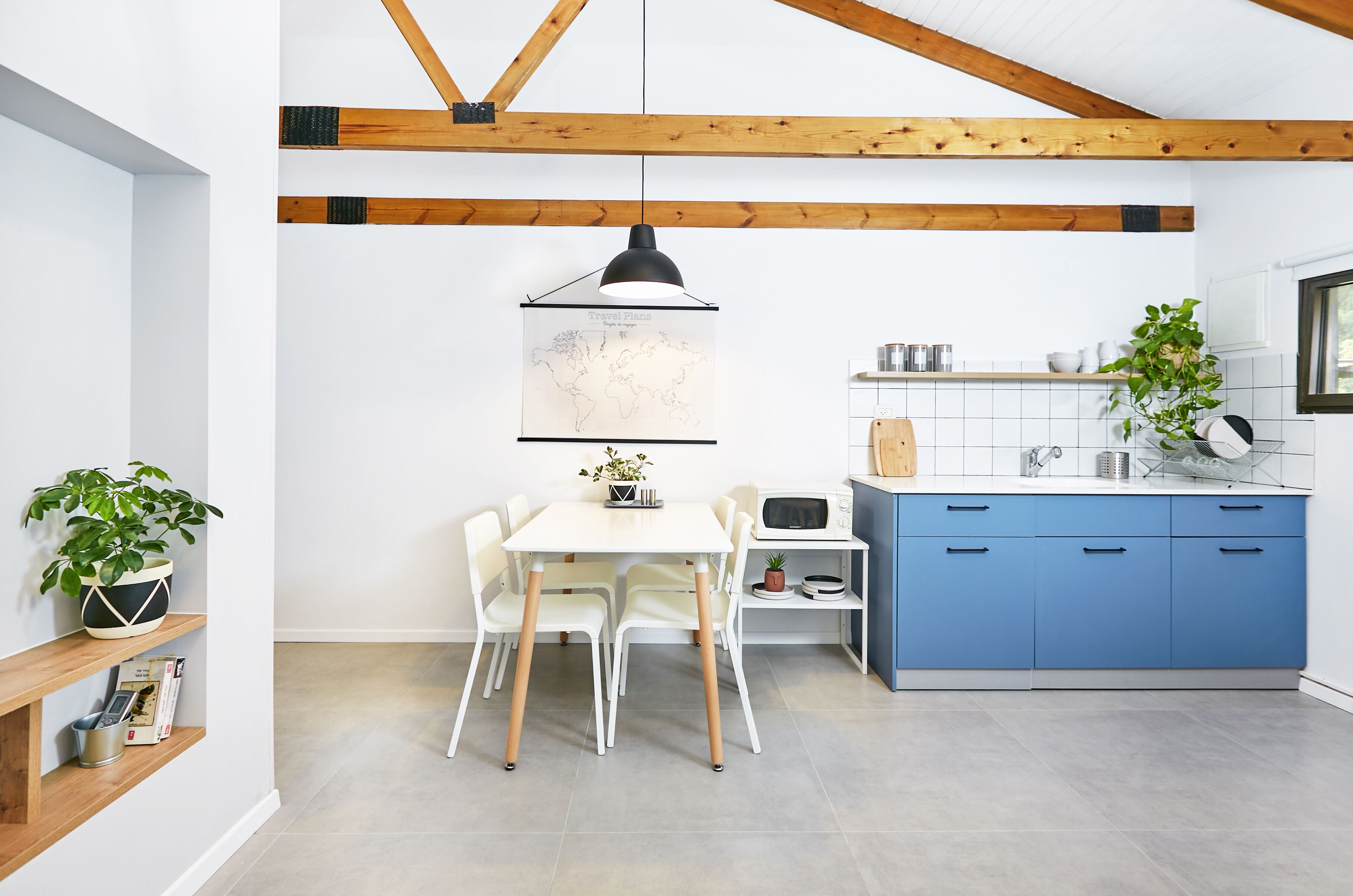 A modern kitchen with a white table, blue cabinets, and a map on the wall.