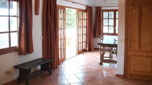 Una habitación con un banco de madera, una mesa y una puerta.
