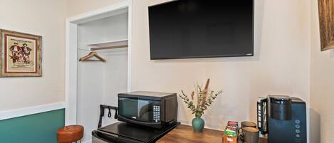 A kitchenette with a microwave, coffee maker, and a small cabinet.