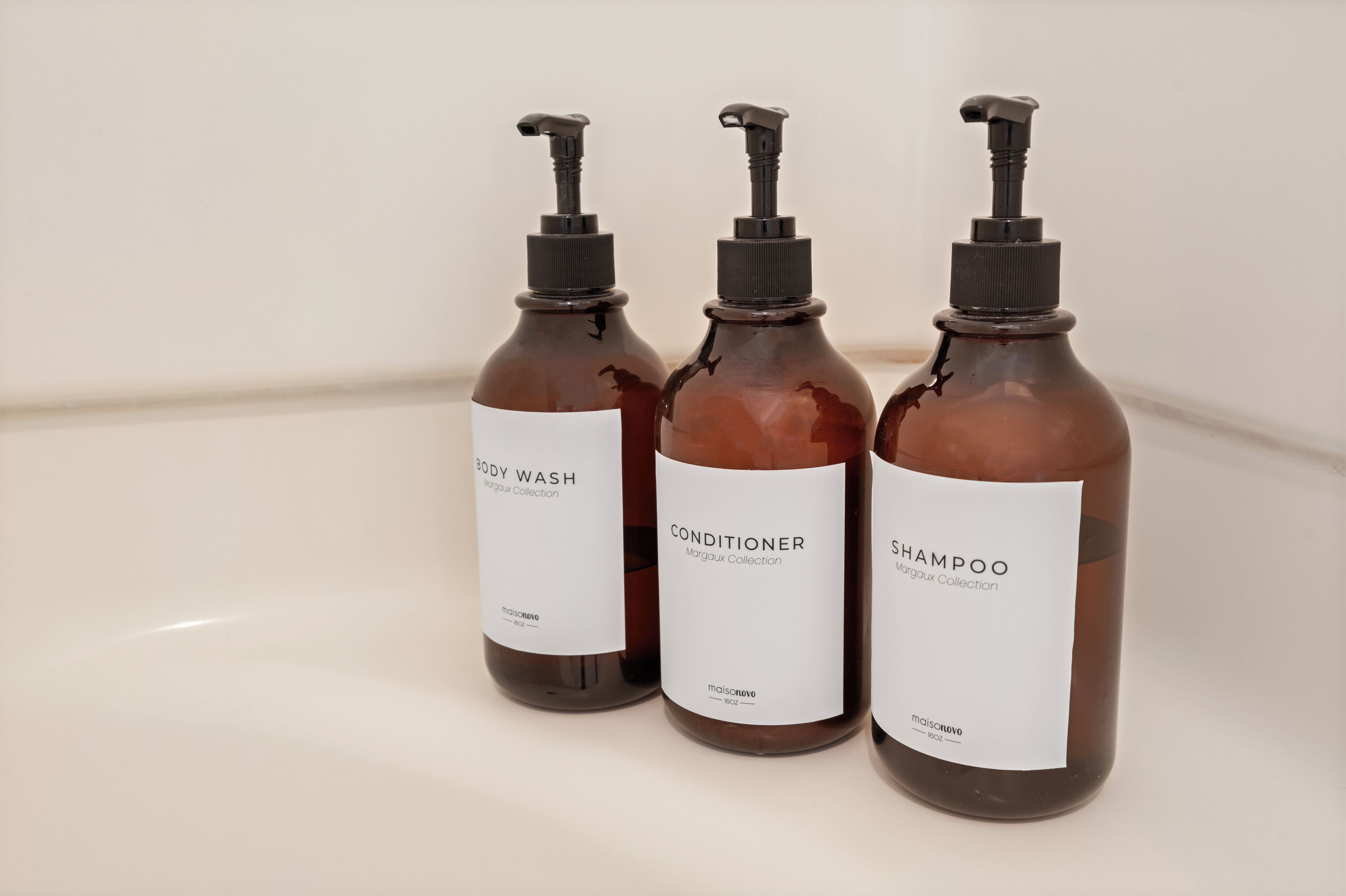 Three bottles of body wash, conditioner, and shampoo on a white surface.