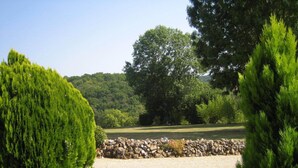 Um jardim bem cuidado, com sebes podadas, um caminho de cascalho e um muro de pedra.
