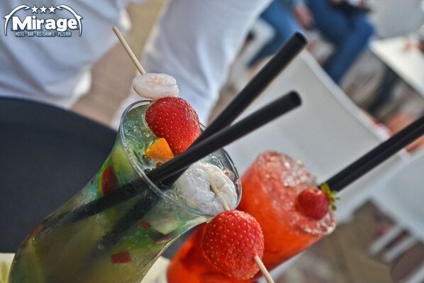 Dos cócteles con guarniciones de frutas y pajitas, servidos en vasos.