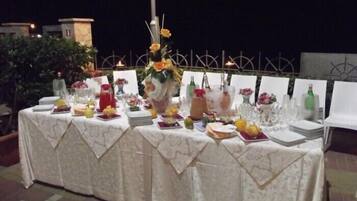 Zona pranzo all'aperto con tavoli apparecchiati per un pasto, con una varietà di piatti e bevande.