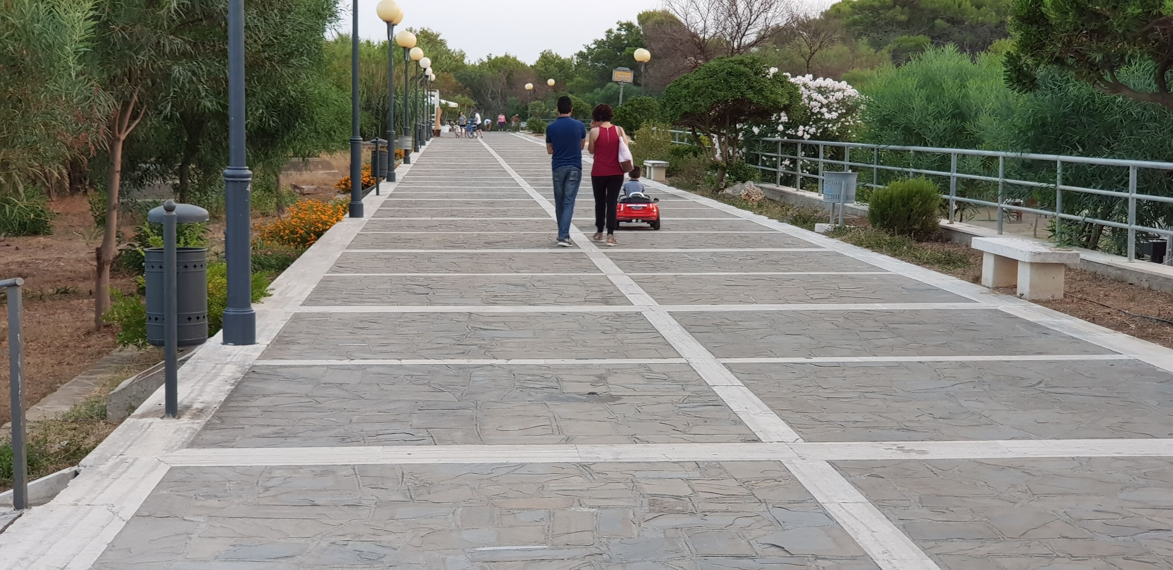 A paved pathway with stone tiles and a metal railing on one side.
