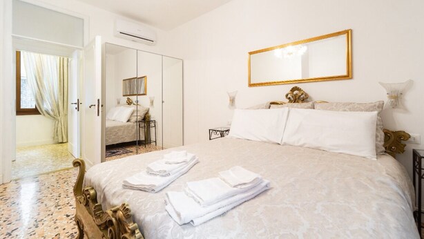 A hotel room with a bed, a mirror, and a door leading to a bathroom. - Ca Maria, bright and quite apartment in Venice  (Venezia)