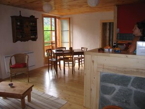 A cozy room with a dining table, chairs, a wicker chair, a small table, and a stone fireplace.