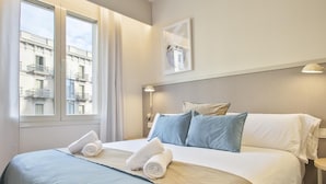 Une chambre d’hôtel avec un lit, une table de chevet, une lampe et une fenêtre avec des rideaux.