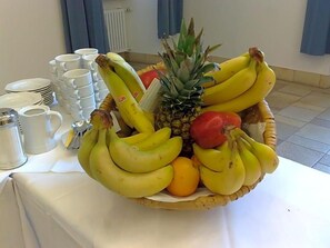 A table with a fruit basket containing bananas, a pineapple, and an orange.