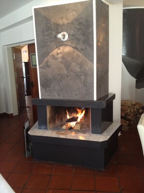 Ein moderner Kamin mit Steinverkleidung und sichtbarem Feuer.