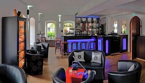 A bar area with stools, a counter, and a bar stocked with bottles.