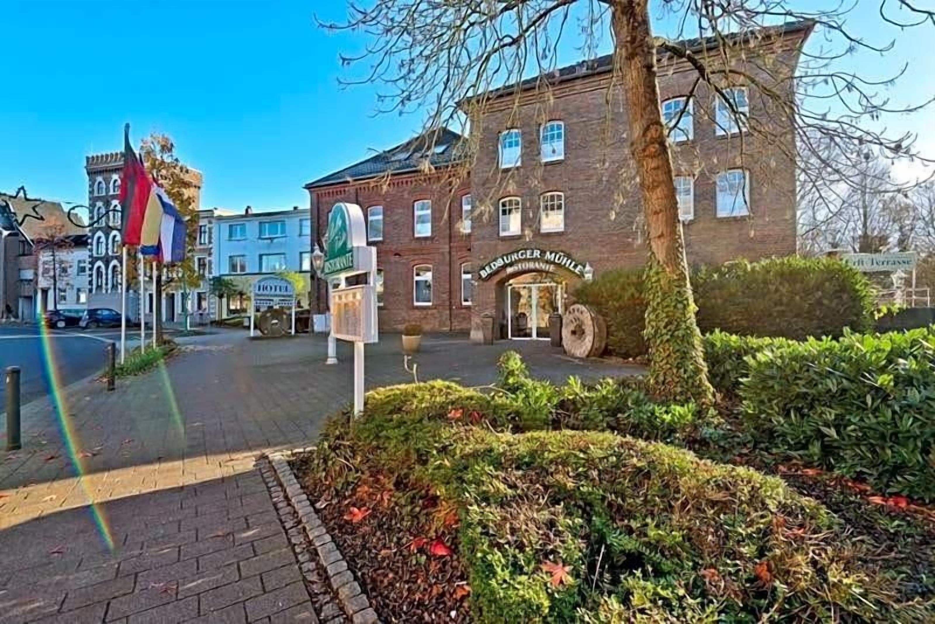 Ein traditionelles Gebäude mit einem Schild für 'Hotel Mühle' und einem großen Wasserrad davor.