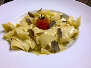 A plate of pasta with a cherry tomato garnish.