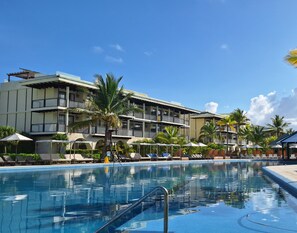 A hotel with a swimming pool, multiple balconies, and palm trees. - El Beso Adults Only At Ocean El Faro - All Inclusive (Punta Cana)