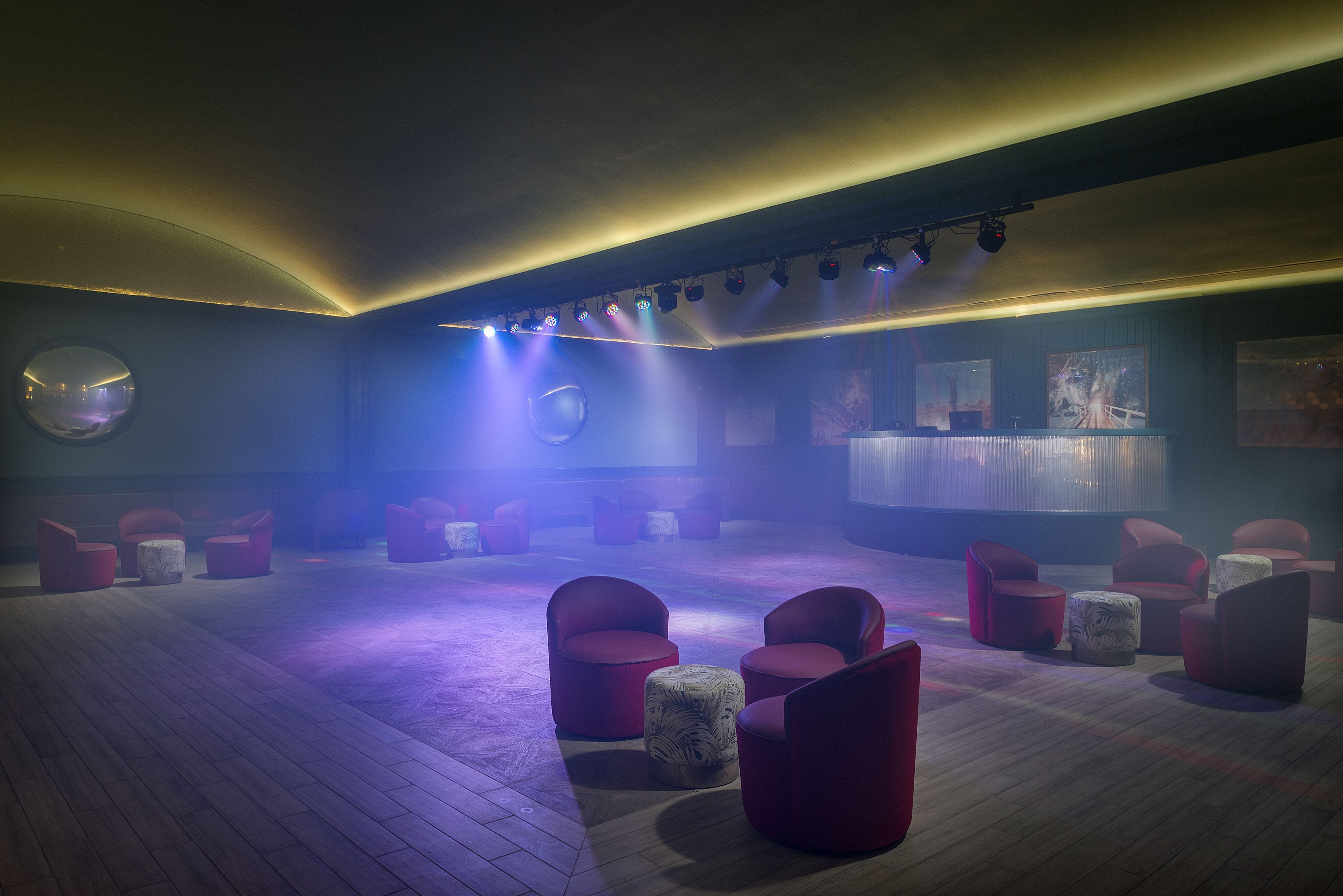 A dimly lit room with red seating and a circular mirror on the wall.