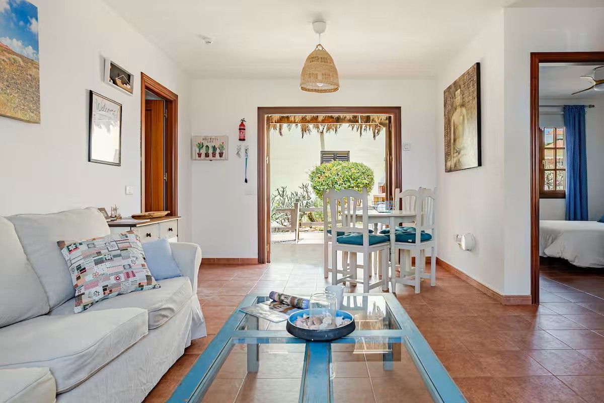 Una sala de estar con un sofá, una mesa de centro y una zona de comedor con sillas y una mesa.