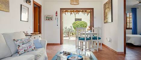 Una sala de estar con un sofá, una mesa de centro y una zona de comedor con sillas y una mesa.