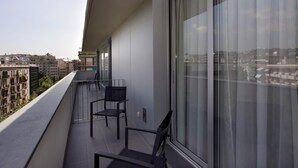 A balcony with two chairs, large windows, and a view of the cityscape.