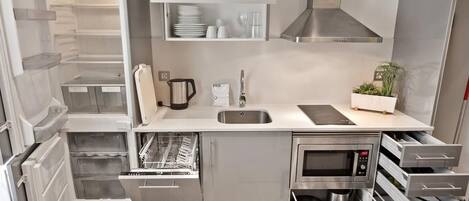 A compact kitchen with a built-in dishwasher, a microwave, and a stainless steel range hood.