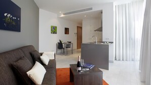 Una sala moderna con un sofá gris, una mesita de centro pequeña y una zona de comedor al fondo.