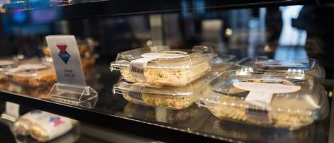 Una vitrina con diversos alimentos envasados, incluyendo ensalada de macarrones y otros platos preparados.