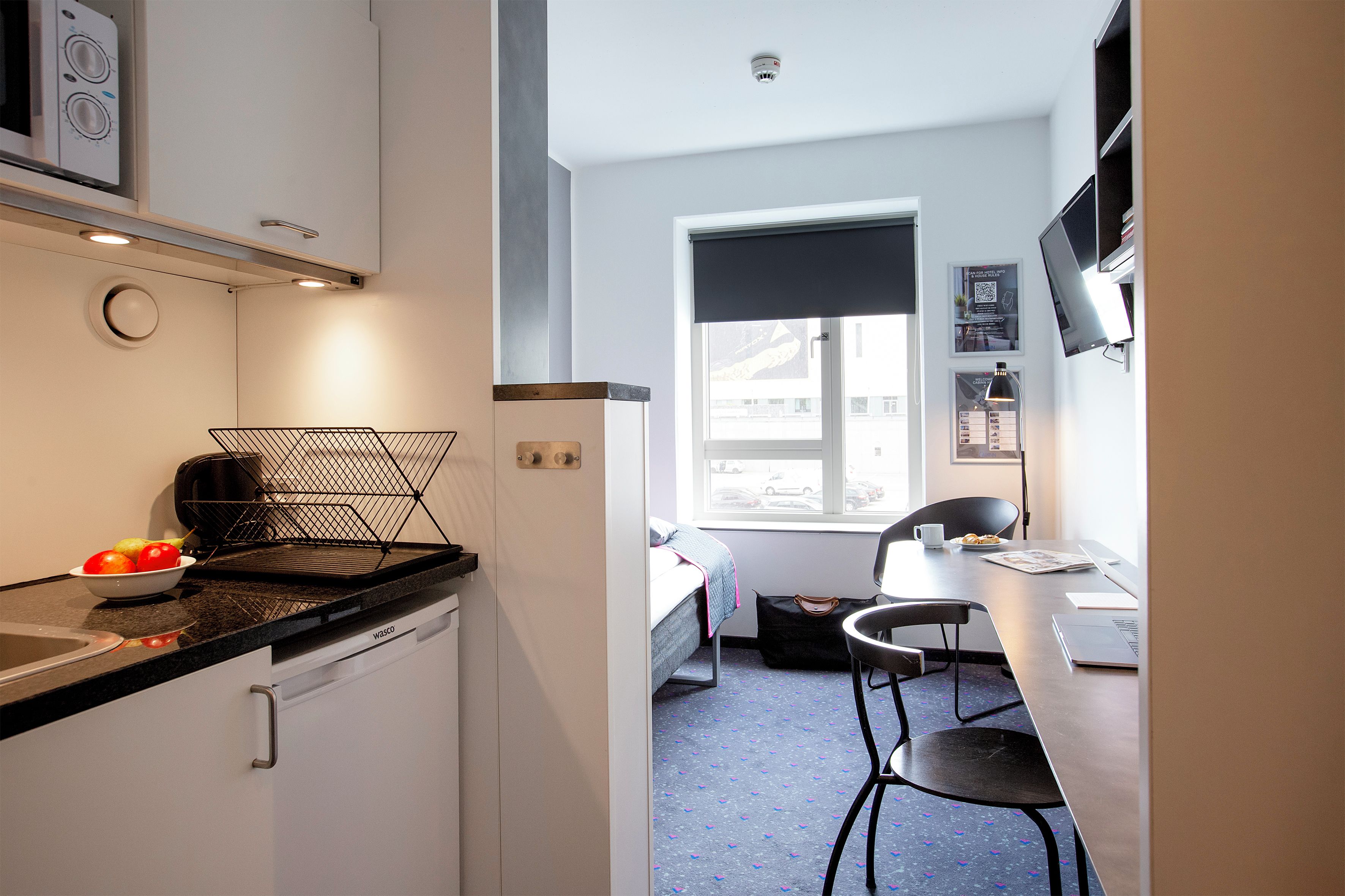 A compact kitchen with a microwave, a kettle, and a fruit bowl.