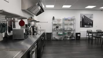 A modern kitchen with stainless steel appliances, a red pot hanging, and a black and white cityscape poster on the wall.