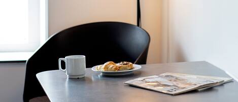 A modern office space with a desk, a chair, a coffee cup, a plate of croissants, a lamp, and framed informational posters on the wall.
