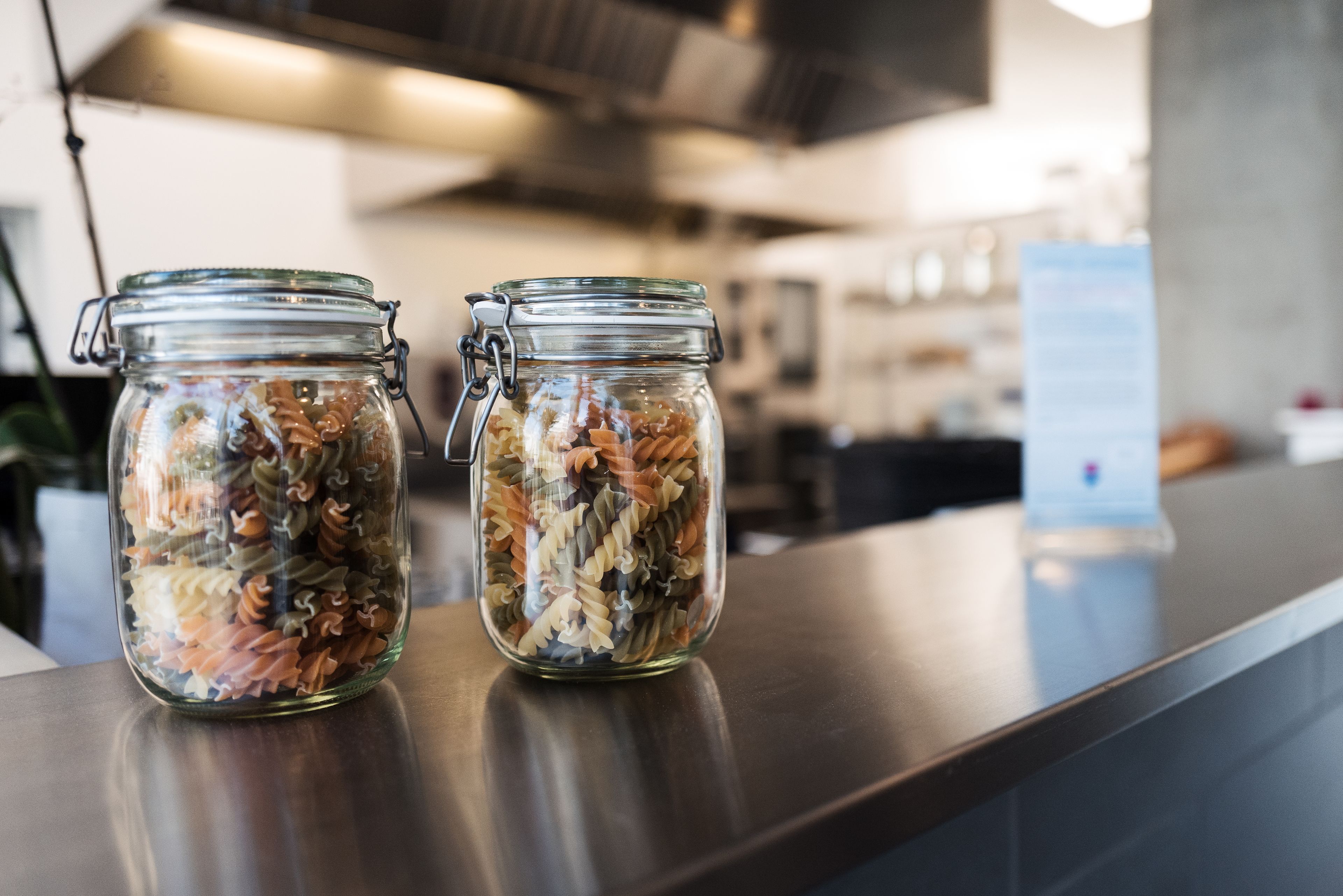 Two glass jars filled with pasta on a counter in a kitchen setting.