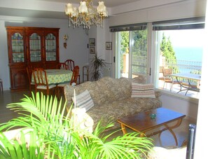 Relax in this stylish living room with a sofa, dining table, and chandelier, offering a balcony view.
