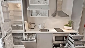 A compact kitchen with a built-in dishwasher, a microwave, and a stainless steel range hood. - One-bedroom apartment with street views (Barcelona)