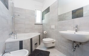 Tina con regadera, toallas, jabón, papel de baño