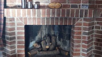 A brick fireplace with a plaque, metal containers, and logs.