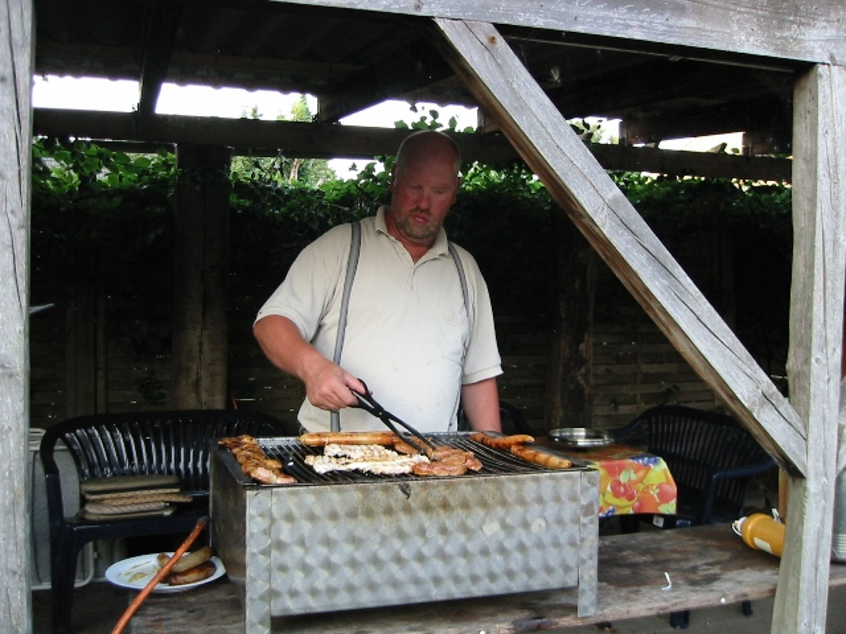 Un hombre preparando comida en una barbacoa al aire libre.