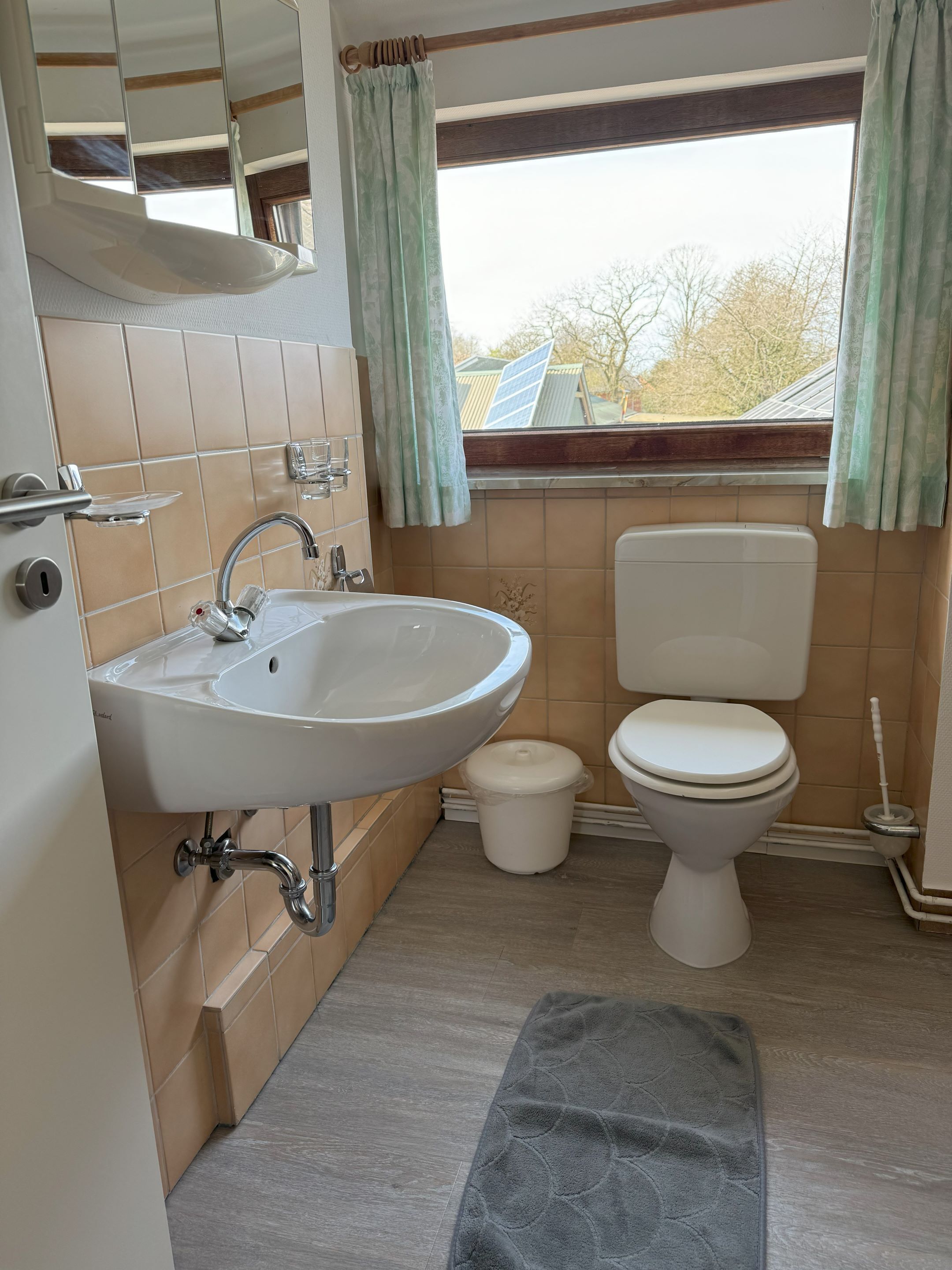 Een badkamer met een wastafel, toilet en raam.